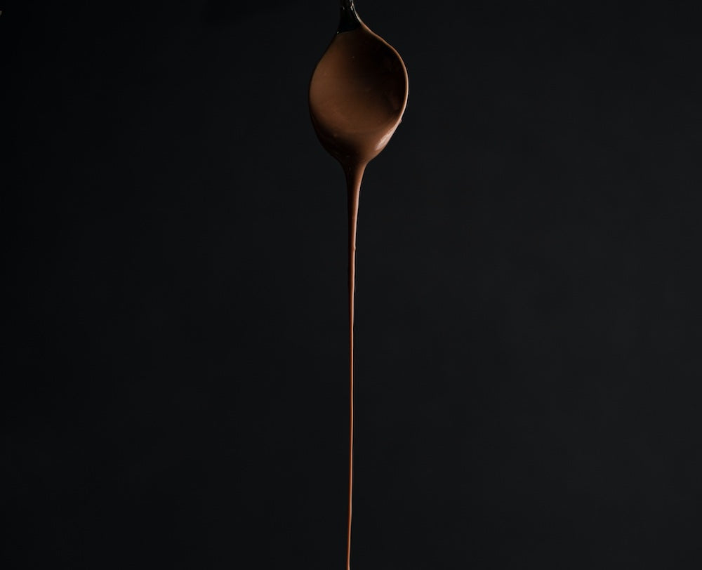 choolate drizzling down in a slim stream from a spoon